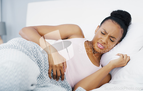 Image of Stomach, pain and problem with woman in bed for menstruation, medical and pms. Endometriosis, healthcare and period with person suffering in bedroom at home for uncomfortable, bloated and sad