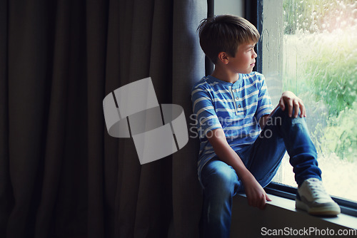 Image of Boy child, rain and thinking by window with sad face, mental health and mockup space in home. Male kid, raining and think by glass with depression, mock up or fear with problem, winter and frustrated