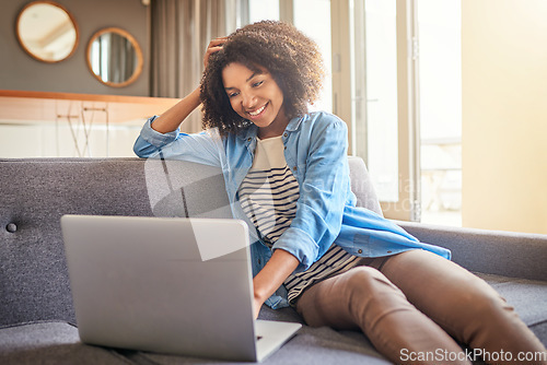 Image of Technology, black woman with laptop and on sofa of her living room at her home smiling. Social media or connectivity, networking and African female reading an email on her digital device on couch