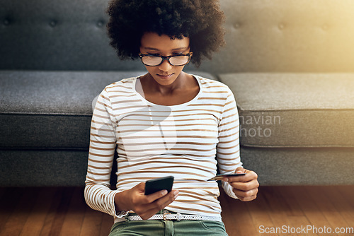 Image of Black woman, phone and credit card for ecommerce, payment or purchase in living room at home. African female person or shopper sitting on floor with smartphone or debit for online shopping or banking