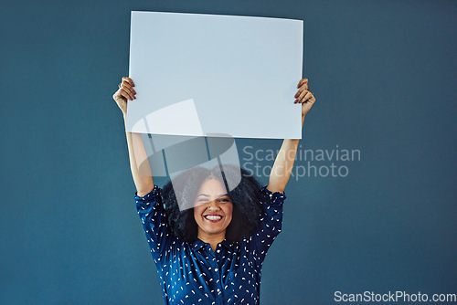 Image of Poster, mockup and portrait of happy woman in studio with banner for news, social media or advertising on blue background. Space, sign and female smile with paper, board and branding promotion
