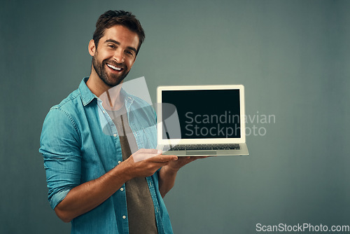 Image of Happy man, laptop and mockup screen for advertising or marketing against a grey studio background. Portrait of male person with smile showing computer display or copy space for branding advertisement