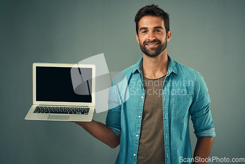 Image of Happy man, laptop and mockup screen for advertising or marketing against a grey studio background. Portrait of male person with smile showing computer display or mock up space for advertisement