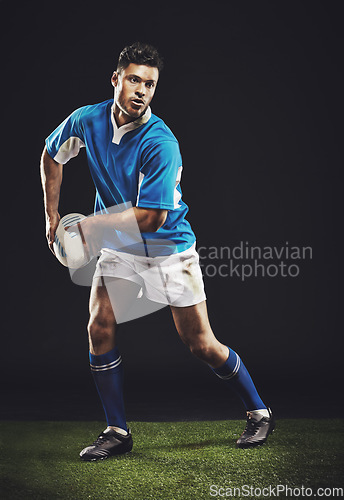 Image of Rugby, passing and man athlete running in dark studio background while training, wellness and fitness sport. Exercise, workout and professional career of sports male person or player on grass