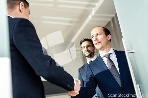 Image of Group of confident business people greeting with a handshake at business meeting in modern office or closing the deal agreement by shaking hands.