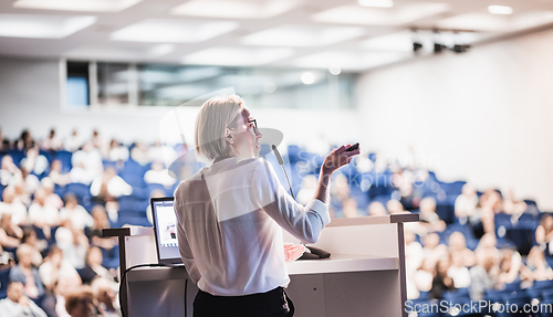 Image of Female speaker giving a talk on corporate business conference. Unrecognizable people in audience at conference hall. Business and Entrepreneurship event.