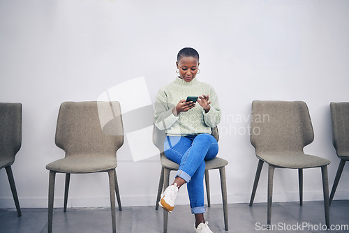 Image of Black woman, phone and sitting on a chair in a waiting room with internet connection for social media. African female person in line for recruitment interview with a smartphone for communication app