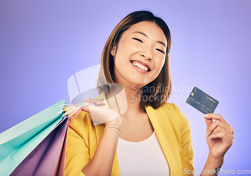 Image of Asian woman, credit card and shopping bag in studio portrait with smile for deal, sale or discount by background. Japanese girl, retail and happy with banking, budget or luxury by purple background