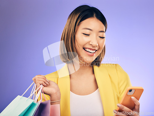 Image of Asian woman, phone and shopping bag in studio, texting and smile for deal, sale or discount by background. Japanese girl, retail and happy with social media, contact and luxury by purple background