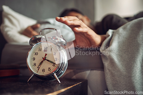 Image of Alarm clock, wake up and man sleeping in the bedroom of his modern apartment in the morning. Lazy, resting and hand of male person taking a nap and dreaming in bed with time watch at his home.