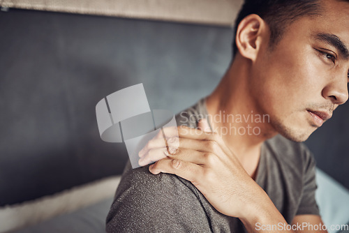 Image of Stress, sick and man with shoulder pain in his bedroom in recovery from an accident or injury. Illness, medical emergency and male person holding a sprain back muscle while resting in his apartment.