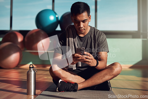 Image of Gym, phone and man on floor with mobile app for fitness schedule, reading email or checking social media. Internet search, cellphone and workout, healthy male athlete on mat in pilates or yoga studio