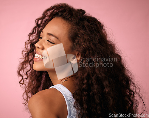 Image of Beauty, hair care and young woman in a studio with a natural, long and curly hairstyle. Happy, smile and profile of a brunette female model with a keratin salon treatment isolated by pink background.