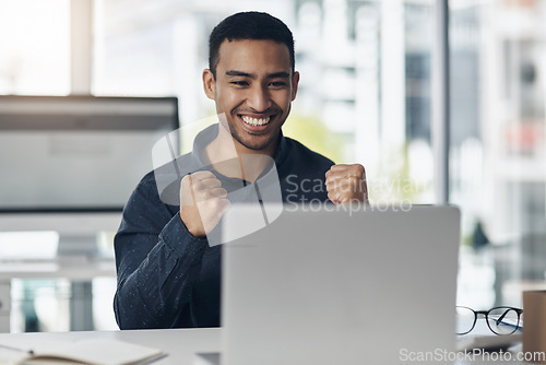 Image of Young business man, celebration and laptop with smile, winning or success on stock market in office. Indian businessman, computer and winner fist to celebrate profit, bonus or online gambling at desk