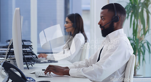 Image of Black man, call center and computer with typing in office for email communication, tech support or telemarketing. Crm, consulting and african agent with woman, pc and customer service in workplace