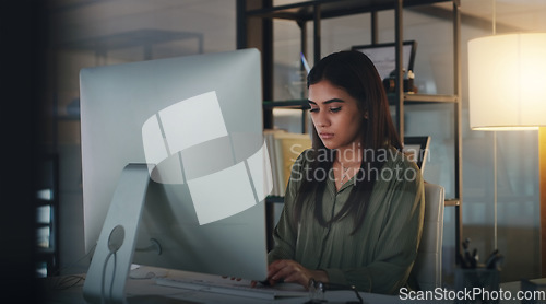 Image of Computer, night and typing with a woman editor working in her office for a journalism or news report. Focus, editing and reporting with a young journalist at work on a desktop for online content