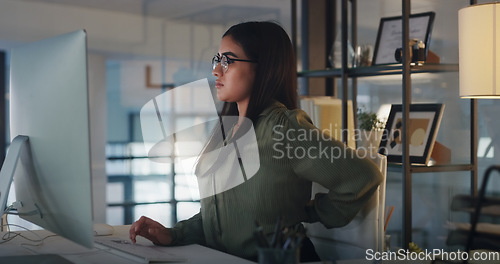 Image of Business woman, back pain and computer at night in office with stress, burnout or crisis. Female entrepreneur at a desk with tech, fatigue and backache while tired of deadline or internet problem