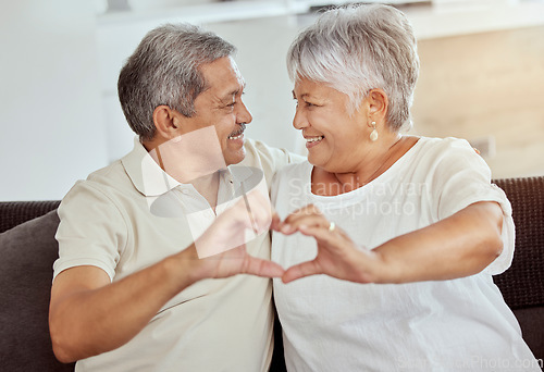 Image of Heart, hands and senior couple on sofa with love, care and trust in their home together. Emoji, fingers and old people in living room with loving marriage, smile or happy in retirement in their house