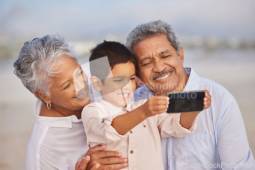 Image of Selfie, smile and grandparents with child at beach for vacation, bonding and generations. Picture, happy and young boy with senior man and woman in nature for travel, happiness and technology