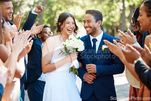 Image of Couple, wedding and guests clapping hands in celebration of love, romance and union. Happy, smile and young bride with a bouquet and groom walking by crowd cheering for marriage at an outdoor event.