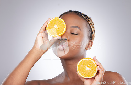 Image of Beauty, orange and kiss with black woman in studio for natural, cosmetics and vitamin c. Nutrition, diet and detox with face of female model on grey background for citrus fruit and health product