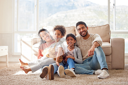 Image of Happy, love and portrait of a family in the living room sitting on the carpet in their house. Happiness, smile and children relaxing on the floor with their parents in the lounge of a modern home.