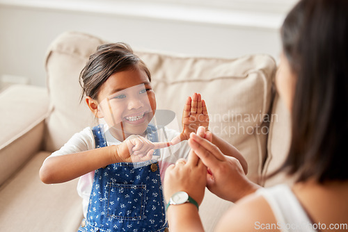 Image of Sign language, learning and girl kid with her mother in the living room of their family home. Happy, smile and child speaking with her hands to her deaf mom to communicate in their modern house.