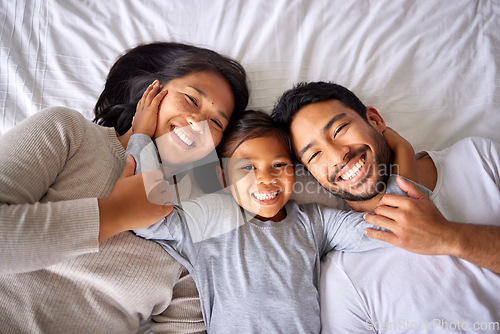 Image of Portrait, love and family in bed from above happy, smile and bonding in their home together. Face, girl child and top view of parents with their daughter in a bedroom, relax and embracing indoors