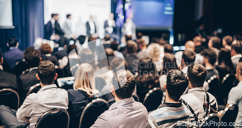 Image of Speaker giving a talk in conference hall at business event. Rear view of unrecognizable people in audience at the conference hall. Business and entrepreneurship concept.