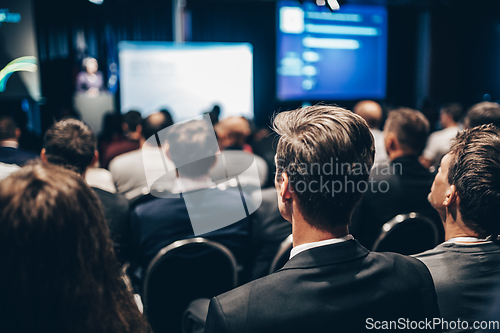 Image of Speaker giving a talk in conference hall at business event. Rear view of unrecognizable people in audience at the conference hall. Business and entrepreneurship concept.