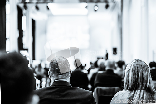 Image of Speaker giving a talk in conference hall at business event. Rear view of unrecognizable people in audience at conference hall. Business and entrepreneurship concept. Black and white selenium image