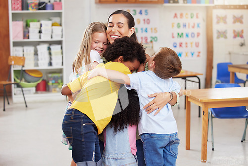 Image of Care, teacher with school children hug and in a classroom with a lens flare. Support or love, happiness or teaching and happy or cheerful woman with kindergarten kids hugging together in a class