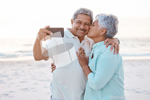 Image of Senior couple, kiss and beach for selfie, profile picture or online post together in nature. Happy elderly woman kissing man on ocean coast for photo, memory or social media vlog in the outdoors