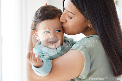 Image of Mom, kiss and holding baby in home for love, care and quality time together to nurture childhood development. Mother, kissing and carrying infant girl kid for support, happiness and comfort of parent