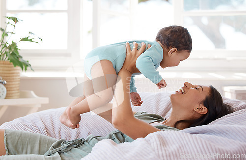 Image of Happy mother, play and holding baby on bed for love, care and quality time together at home. Mom, smile and carrying playful infant kid, newborn and laughing in bedroom for comfort, relax and support