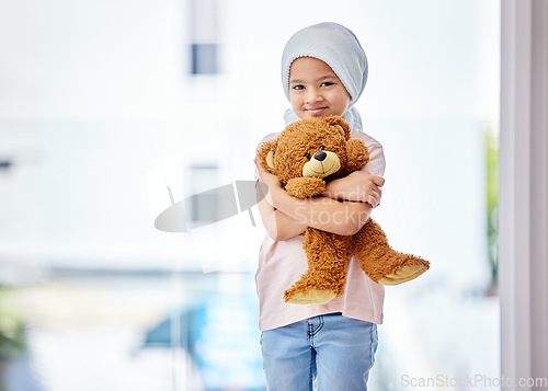 Image of Healthcare, child and portrait of a cancer patient holding a teddy bear for support or comfort. Medical, smile and girl kid with leukemia standing with a toy after treatment in a medicare hospital.