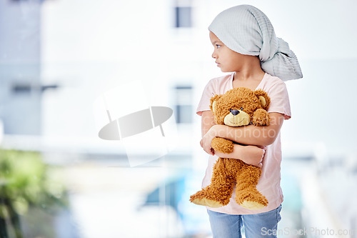 Image of Healthcare, teddy bear and child cancer patient holding her toy for support or comfort. Medical, recovery and girl kid with leukemia standing after treatment or chemotherapy in a medicare hospital.