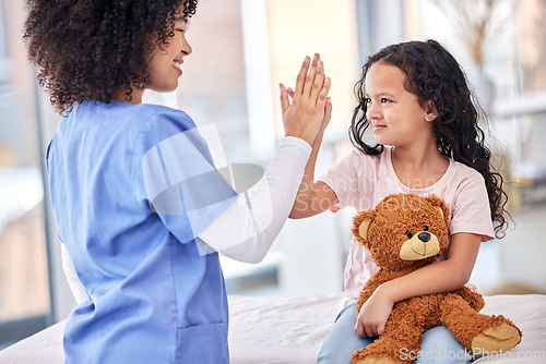 Image of High five, nurse and child on bed in hospital for children, health and support in medical treatment. Pediatrics, healthcare and kid, nursing caregiver touching hands with young patient and teddy bear