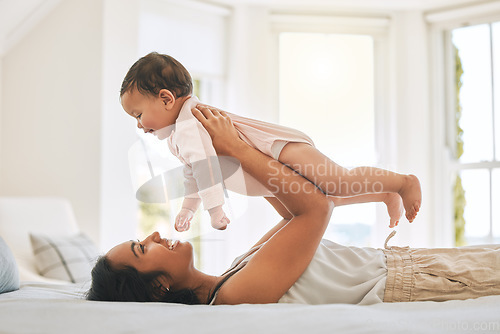 Image of Mother, lifting baby and bedroom in family home for bonding, security or quality time. Happy woman or mom and girl child relax together on bed for development, trust and support or care for happiness