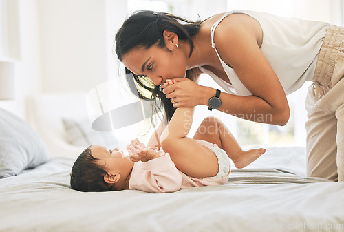 Image of Mother, baby and kiss feet in a family home for bonding, happiness and quality time. Woman or mom and girl child relax together in bedroom for development, trust and support or care on mothers day