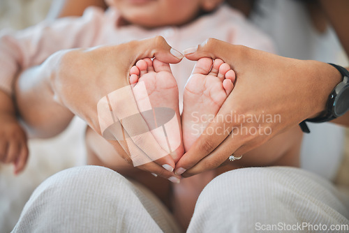 Image of Baby, feet and hands in heart for love, care and nurture childhood development, growth and wellness of kids. Closeup, mother and hand shape around tiny foot of infant, newborn and child for support