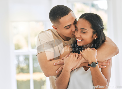 Image of Couple, hug and kiss in home for love, care and relax for romance, support and trust of bonding together. Happy man hugging young woman, partner and kissing for quality time, happiness or anniversary