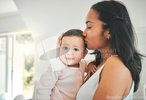 Image of Mother, holding baby and kiss in a family home for love, security and quality time. Woman or mom and girl child relax together in a house for development, trust and support or care on mothers day