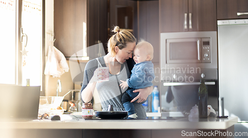 Image of Happy mother and little infant baby boy together making pancakes for breakfast in domestic kitchen. Family, lifestyle, domestic life, food, healthy eating and people concept.