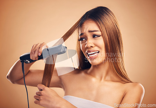 Image of Woman with flat iron, haircare fail and anxiety about heat damage with hairloss isolated on studio background. Electric hair straightener, female model worried about keratin treatment and hairstyle