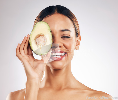 Image of Skincare, smile and woman with avocado in studio for organic, facial or treatment on grey background. Face, avo and girl model with fruit for eco, vegan or skin detox with anti aging or antioxidants