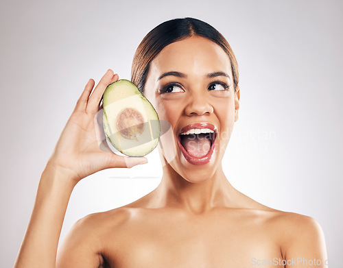 Image of Woman, beauty and avocado in studio, excited and health for wellness, facial glow and white background. Girl, model and healthy skin with fruit, makeup or cosmetics for self care, funny face or smile
