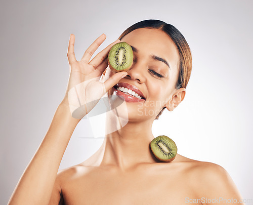 Image of Kiwi, skincare and happy woman in studio for beauty, wellness or self love with natural cosmetic on grey background. Organic, treatment and female model with fruit for hyperpigmentation prevention