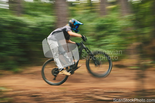 Image of Sports, bike and man doing adrenaline stunt with energy while riding fast for competition practice in woods. Fitness, blur motion and male athlete biker with training or exercise in an outdoor forest