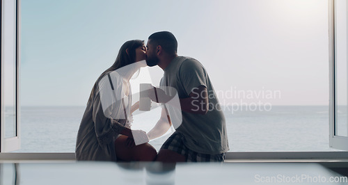 Image of Couple, kiss and coffee in morning by window with love, romance and care on holiday by ocean with sunshine. Man, woman and trust with drink, espresso or matcha on vacation by sea with bond in summer